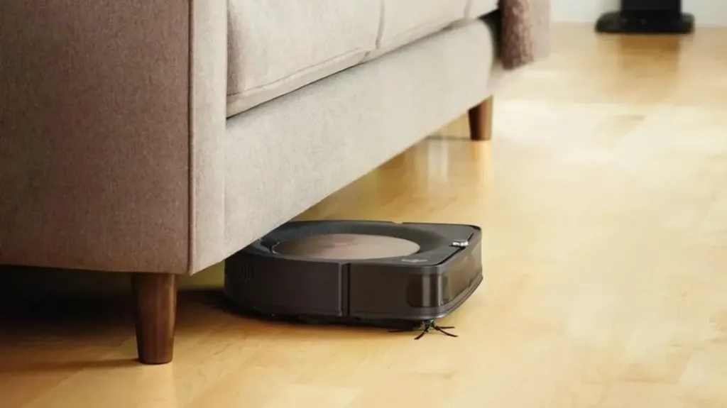 The iRobot Roomba S9+ - one of the best robot vacuums Australia - vacuuming under a lounge on a wooden floor